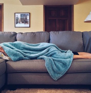 Hvorfor alle burde eje en sovepose Person sover under et tæppe på sofaen