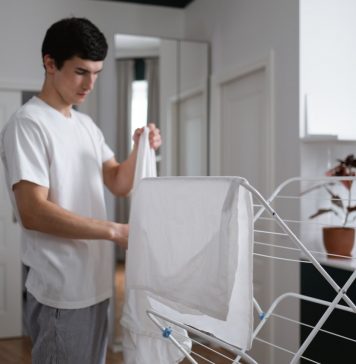 Tør dit tøj på en mere miljøvenlig måde med et tørrestativ Mand tørrer sit tøj på et tørrestativ