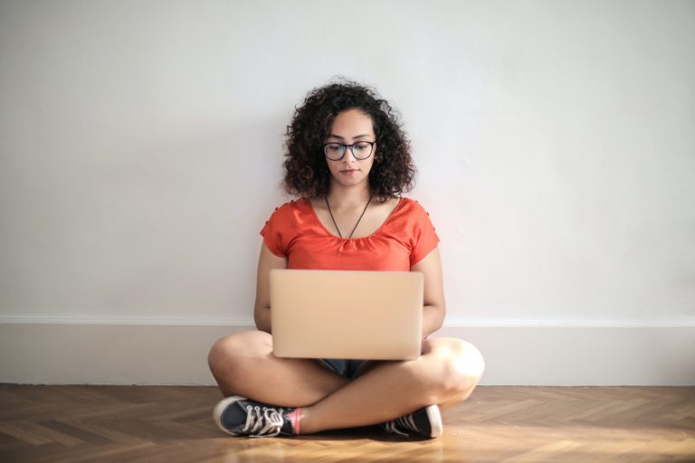 Kvinde sidder på gulv med computer